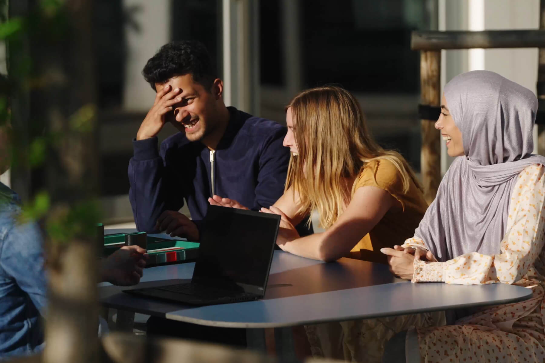 Fire personer ved et Plateau Picnic L bordbænkesæt, de griner og har det godt