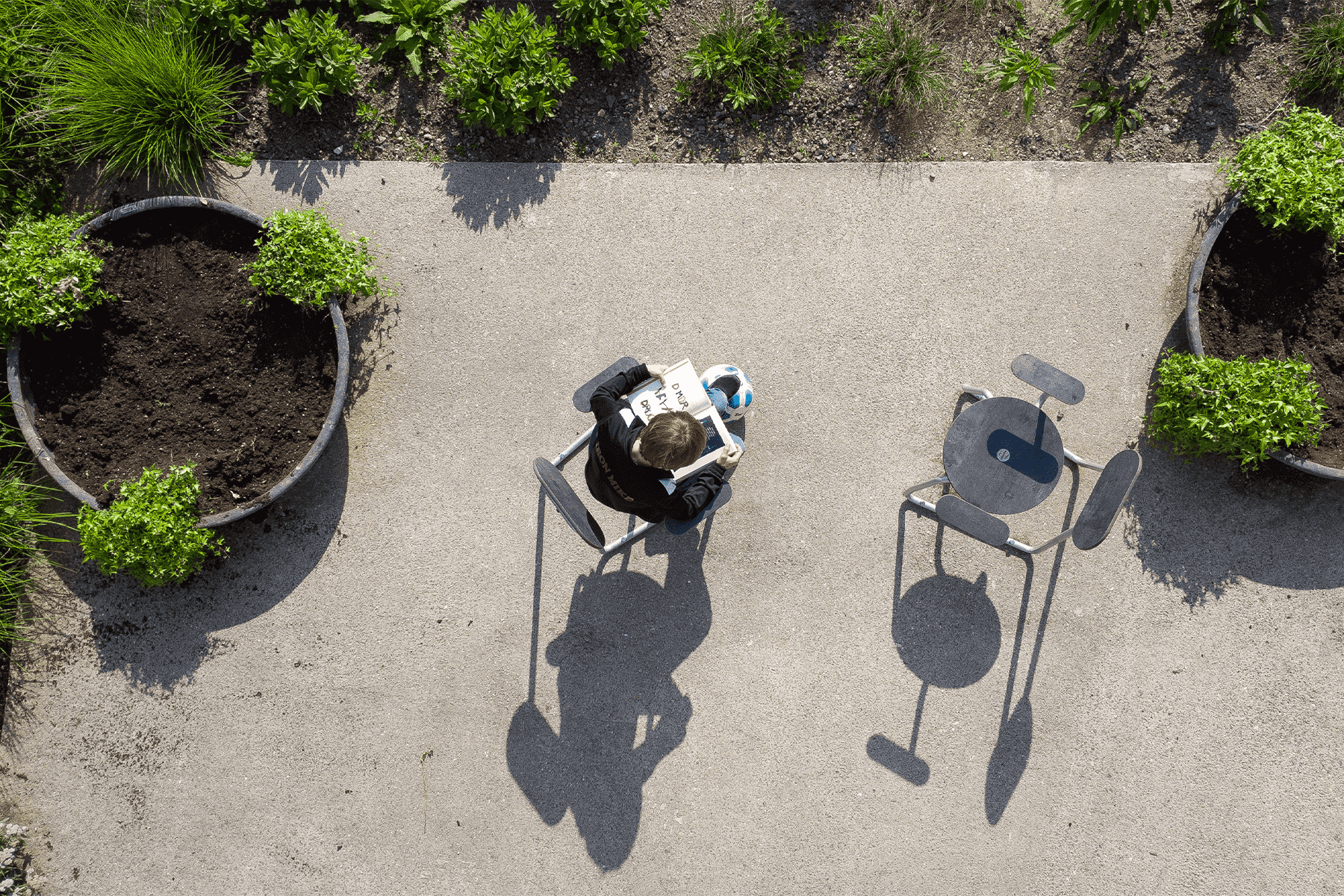 To grå Plateau City Chairs set oppefra, på den ene sidder en mand og læser Avis