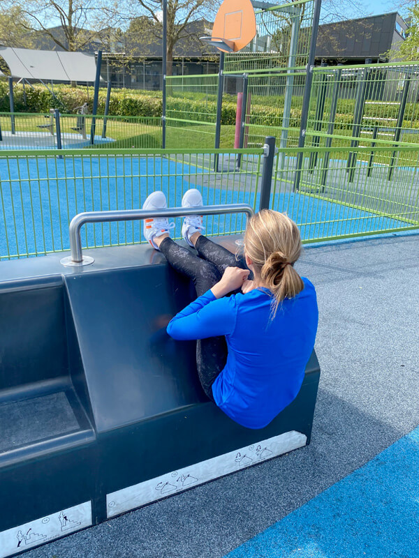 En kvinde, der laver mavebøjninger med en blå FitStation