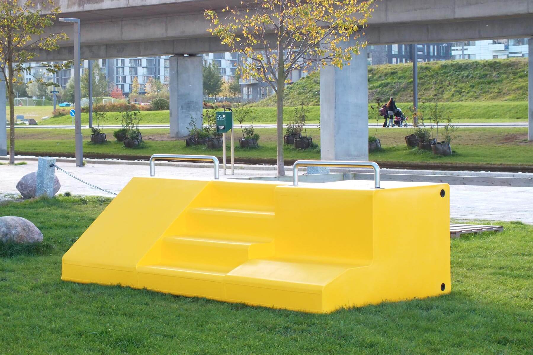 En gul FitStation i et grønt areal i byrummet