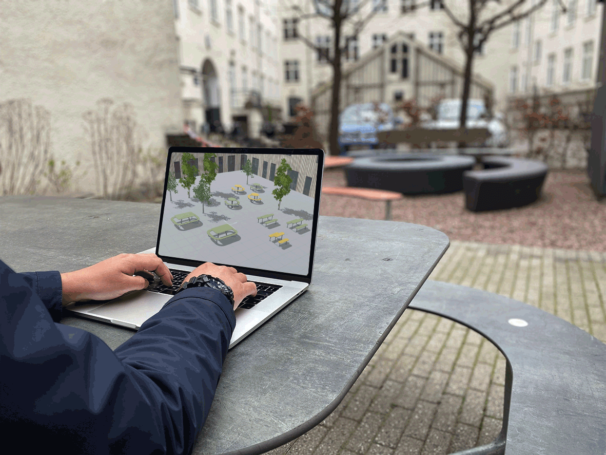 En mand der sidder på Plateau Picnic O bordbænkesæt og bruger ViZU, et virtuelt program på sin computer